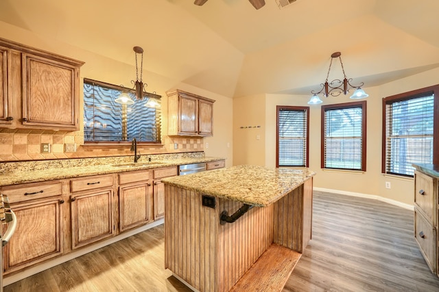 kitchen featuring vaulted ceiling, sink, hanging light fixtures, and a kitchen island