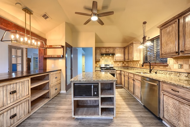 kitchen with pendant lighting, sink, appliances with stainless steel finishes, a kitchen island, and vaulted ceiling