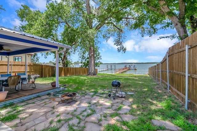 view of yard featuring a water view, an outdoor fire pit, a fenced backyard, and a patio