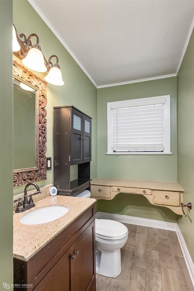 bathroom featuring hardwood / wood-style flooring, ornamental molding, toilet, and vanity