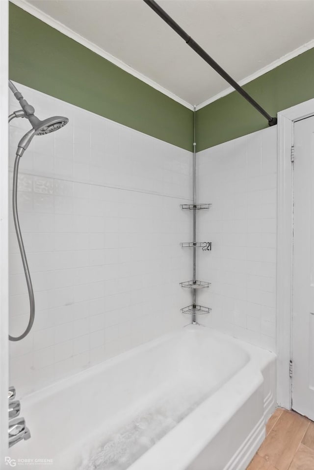 bathroom featuring tiled shower / bath combo, wood-type flooring, and ornamental molding