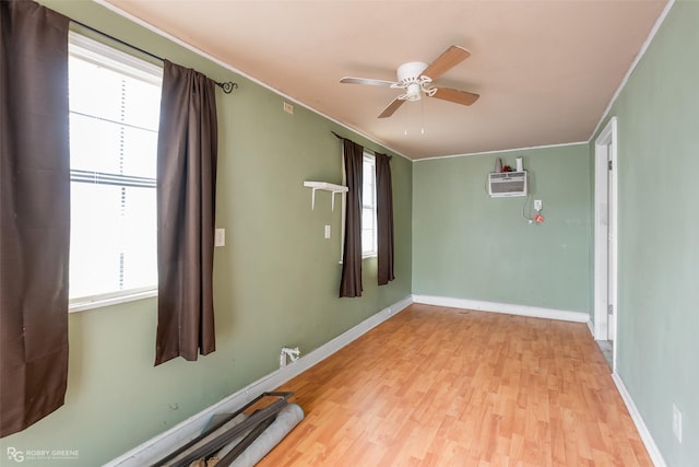 spare room with ceiling fan, an AC wall unit, a healthy amount of sunlight, and light wood-type flooring