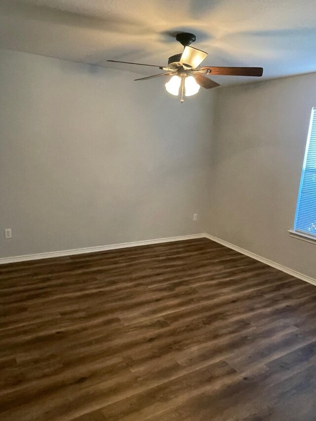 empty room featuring dark wood-type flooring and ceiling fan