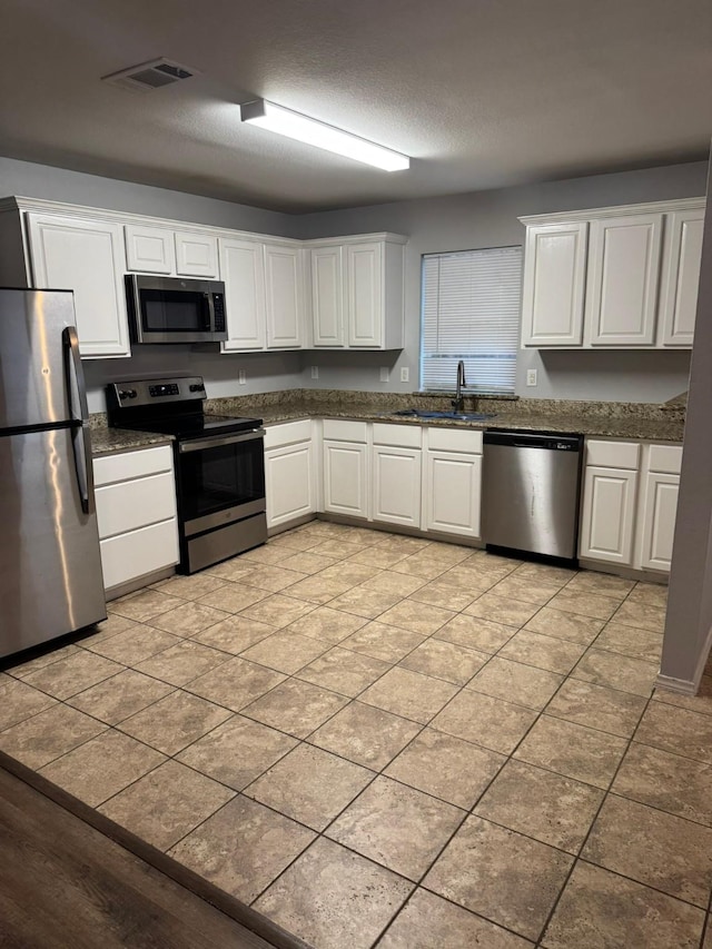 kitchen with stainless steel appliances, white cabinetry, and sink