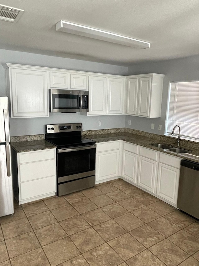 kitchen with appliances with stainless steel finishes, sink, and white cabinets