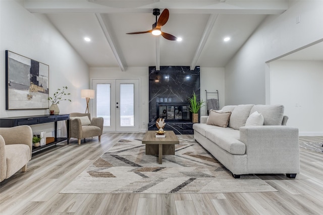 living room featuring ceiling fan, a premium fireplace, lofted ceiling with beams, and light hardwood / wood-style flooring