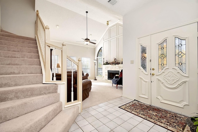 foyer featuring high vaulted ceiling, crown molding, light colored carpet, and ceiling fan