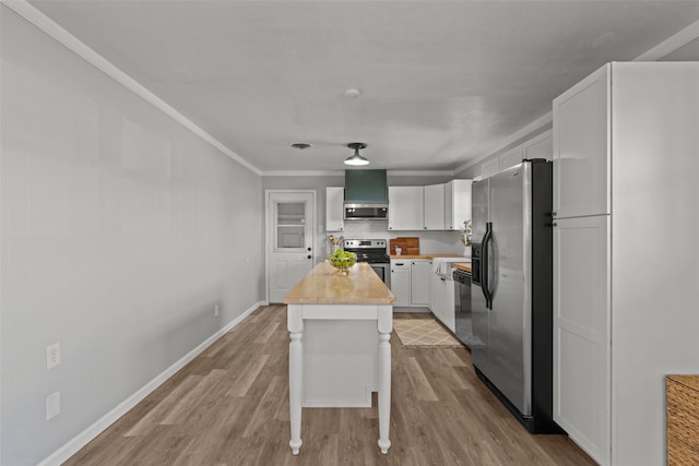 kitchen with a kitchen island, appliances with stainless steel finishes, white cabinets, exhaust hood, and light wood-type flooring