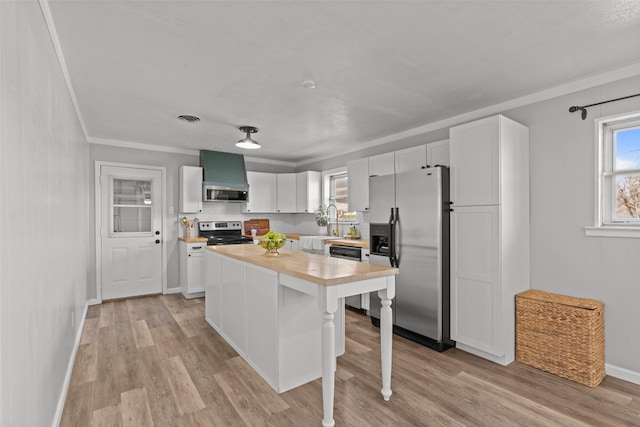 kitchen with a breakfast bar, appliances with stainless steel finishes, white cabinetry, a kitchen island, and light wood-type flooring