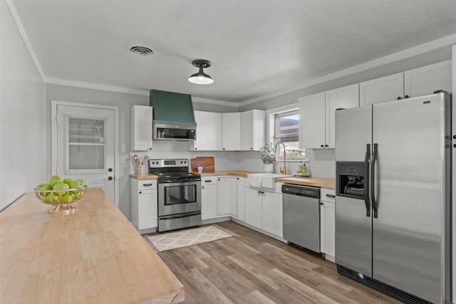 kitchen featuring stainless steel appliances, butcher block countertops, sink, and white cabinets