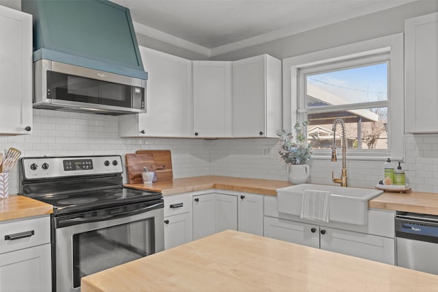 kitchen with butcher block countertops, stainless steel appliances, sink, and white cabinets