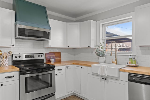 kitchen featuring stainless steel appliances, white cabinetry, butcher block counters, and sink