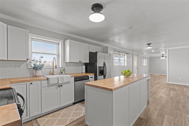 kitchen featuring white cabinetry, stainless steel appliances, sink, and butcher block countertops