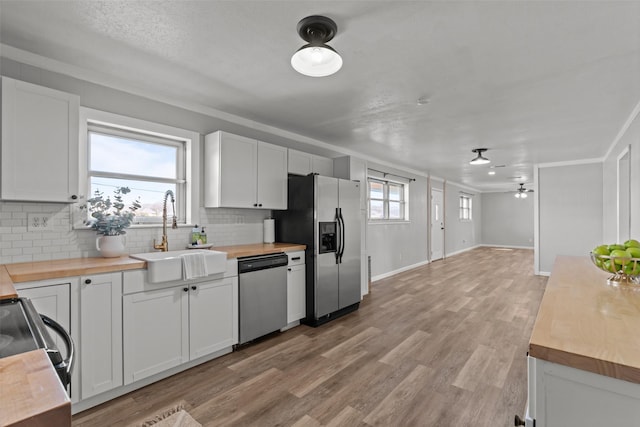 kitchen featuring appliances with stainless steel finishes, white cabinetry, butcher block counters, sink, and light hardwood / wood-style flooring