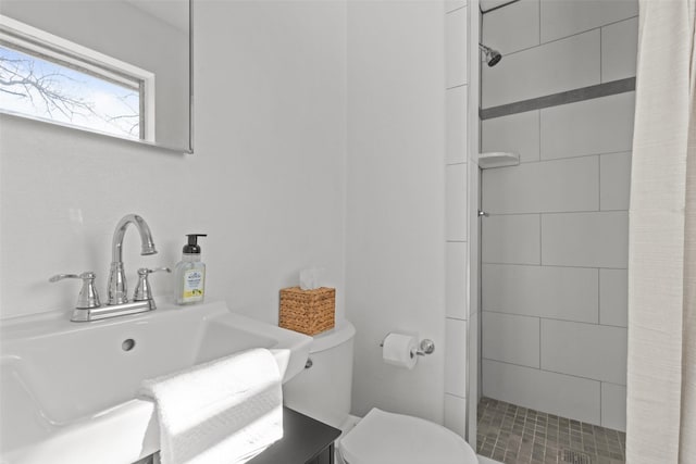 bathroom featuring vanity, a tile shower, and toilet