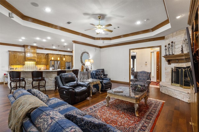 living room featuring dark wood-type flooring, ornamental molding, and a tray ceiling