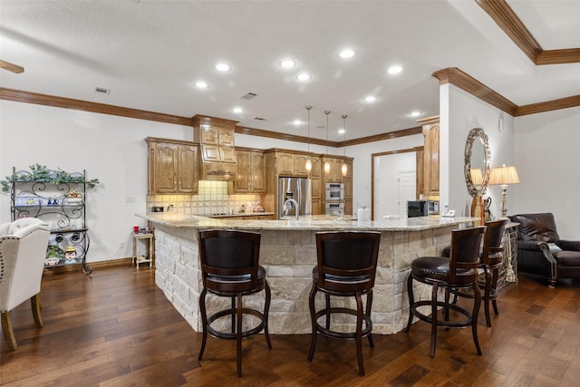 kitchen featuring dark wood-type flooring, appliances with stainless steel finishes, light stone counters, a kitchen bar, and kitchen peninsula