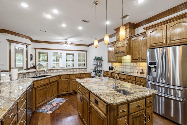 kitchen featuring hanging light fixtures, appliances with stainless steel finishes, a kitchen island with sink, and sink