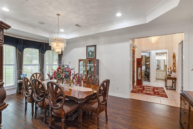 dining room with an inviting chandelier, crown molding, dark hardwood / wood-style flooring, and a raised ceiling