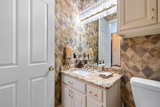 bathroom with vanity, toilet, and tile walls