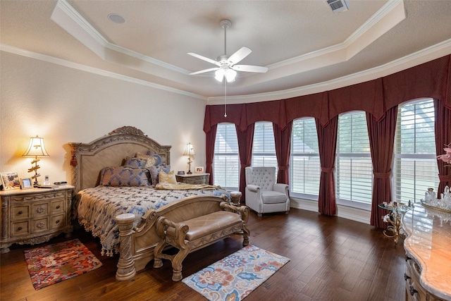 bedroom with a raised ceiling, ornamental molding, and dark wood-type flooring