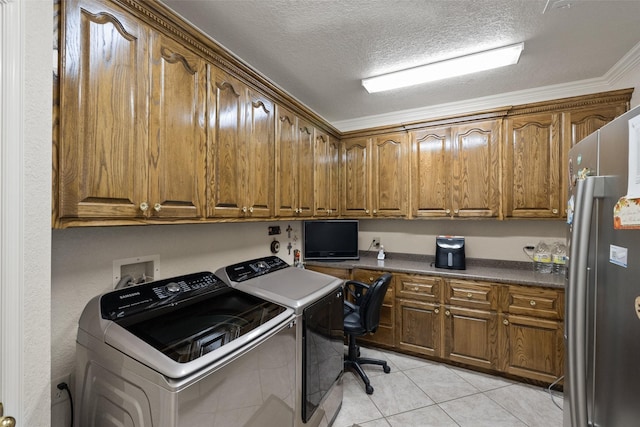 laundry room featuring crown molding, cabinets, a textured ceiling, washing machine and clothes dryer, and light tile patterned flooring