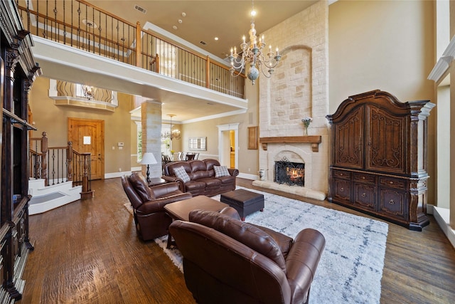 living room featuring an inviting chandelier, a towering ceiling, a fireplace, and dark hardwood / wood-style flooring