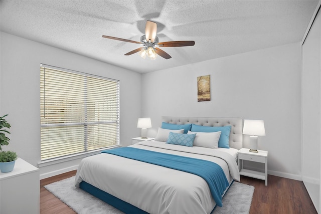 bedroom featuring a ceiling fan, a textured ceiling, baseboards, and wood finished floors