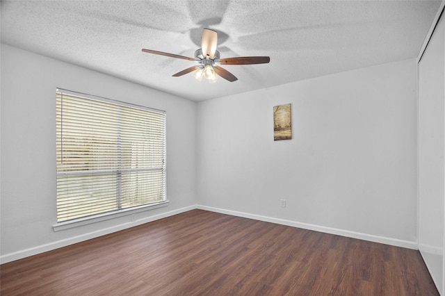 spare room with dark wood-type flooring, a ceiling fan, and baseboards