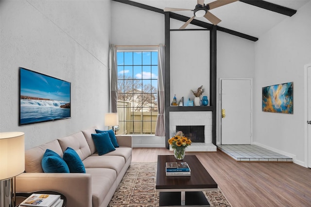 living room with a fireplace, high vaulted ceiling, wood finished floors, and beamed ceiling