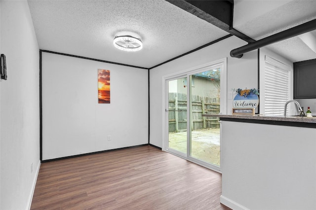 spare room with a textured ceiling, a sink, plenty of natural light, and wood finished floors