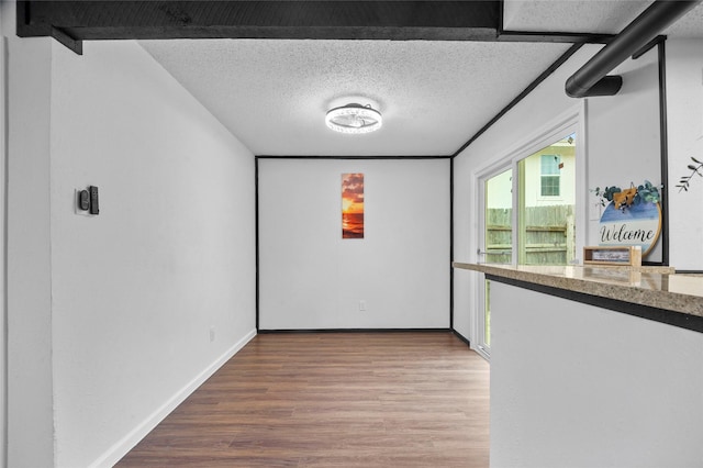 interior space featuring a textured ceiling, baseboards, and wood finished floors