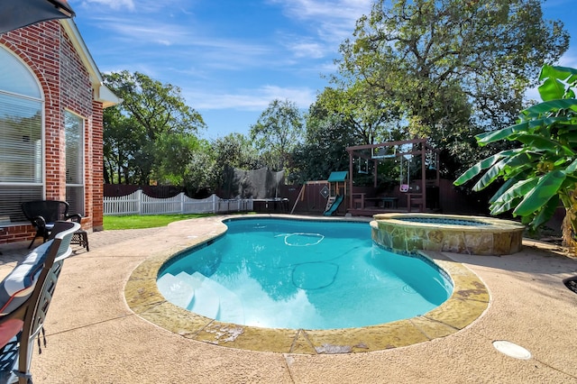 view of swimming pool featuring an in ground hot tub, a trampoline, a playground, and a patio area