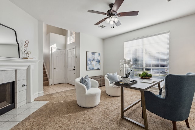 office space with a tiled fireplace, light tile patterned floors, and ceiling fan