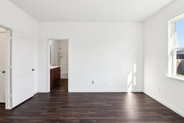 unfurnished bedroom with ensuite bathroom and dark hardwood / wood-style floors