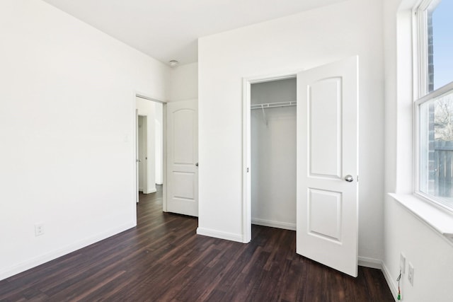 unfurnished bedroom with dark wood-type flooring and a closet