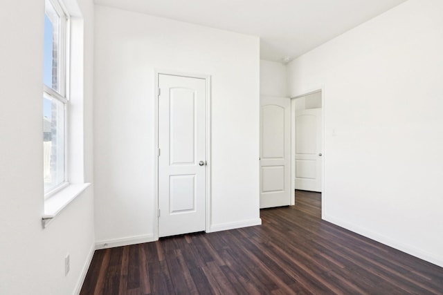 unfurnished bedroom with dark hardwood / wood-style floors and multiple windows