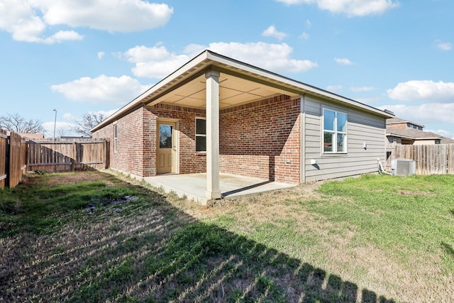 rear view of house featuring central AC unit, a lawn, and a patio