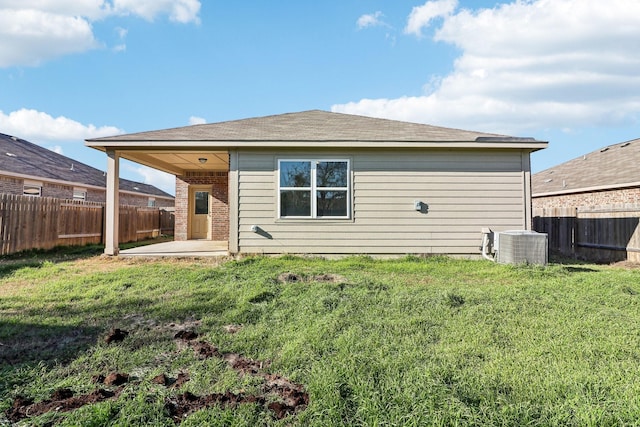 back of house featuring cooling unit, a yard, and a patio