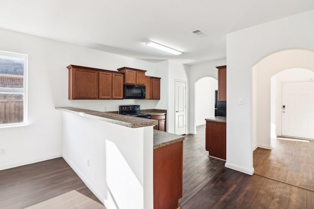 kitchen featuring dark wood-type flooring, black appliances, and kitchen peninsula