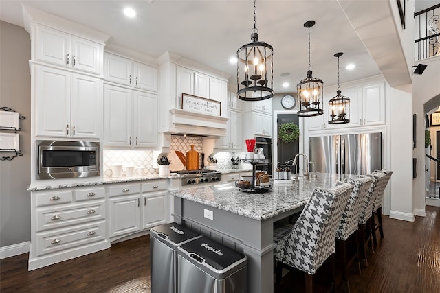 kitchen with white cabinetry, stainless steel appliances, and a center island with sink