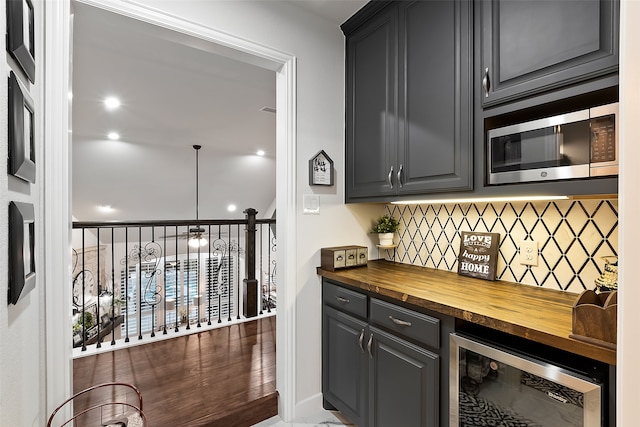 bar featuring wine cooler, butcher block countertops, backsplash, and pendant lighting