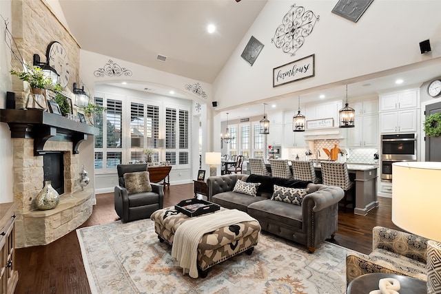 living room featuring hardwood / wood-style floors, a stone fireplace, and high vaulted ceiling