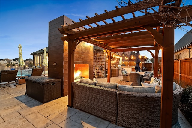 patio terrace at dusk featuring an outdoor kitchen, an outdoor living space with a fireplace, and a pergola