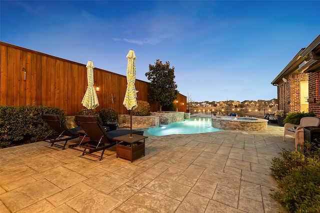 pool at dusk with an in ground hot tub, pool water feature, and a patio area