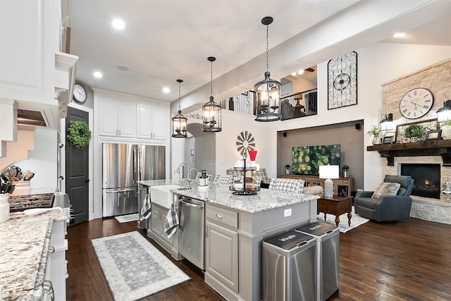 kitchen featuring sink, stainless steel appliances, white cabinets, and a center island with sink