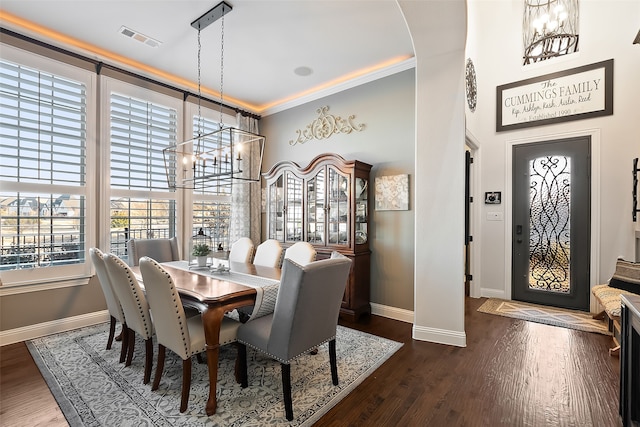 dining room with a notable chandelier, crown molding, and dark wood-type flooring