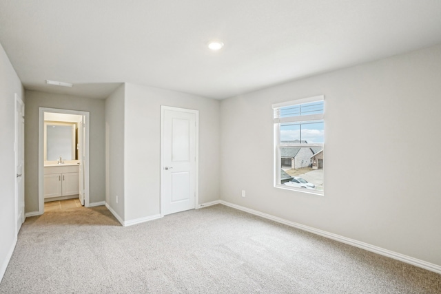 unfurnished bedroom featuring connected bathroom, sink, and light colored carpet