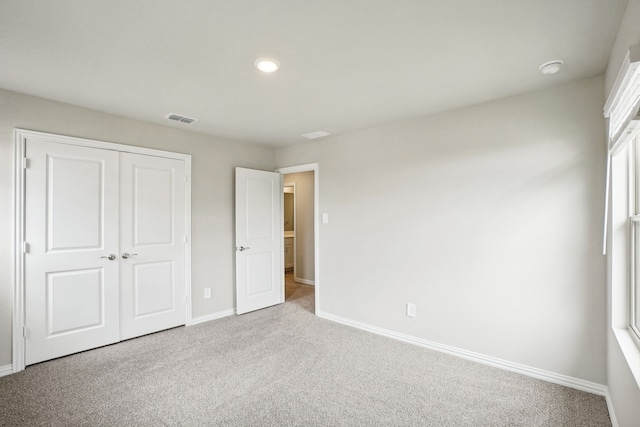 unfurnished bedroom featuring light carpet and a closet