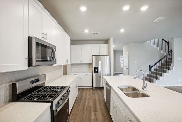 kitchen with appliances with stainless steel finishes, sink, white cabinets, decorative backsplash, and dark wood-type flooring